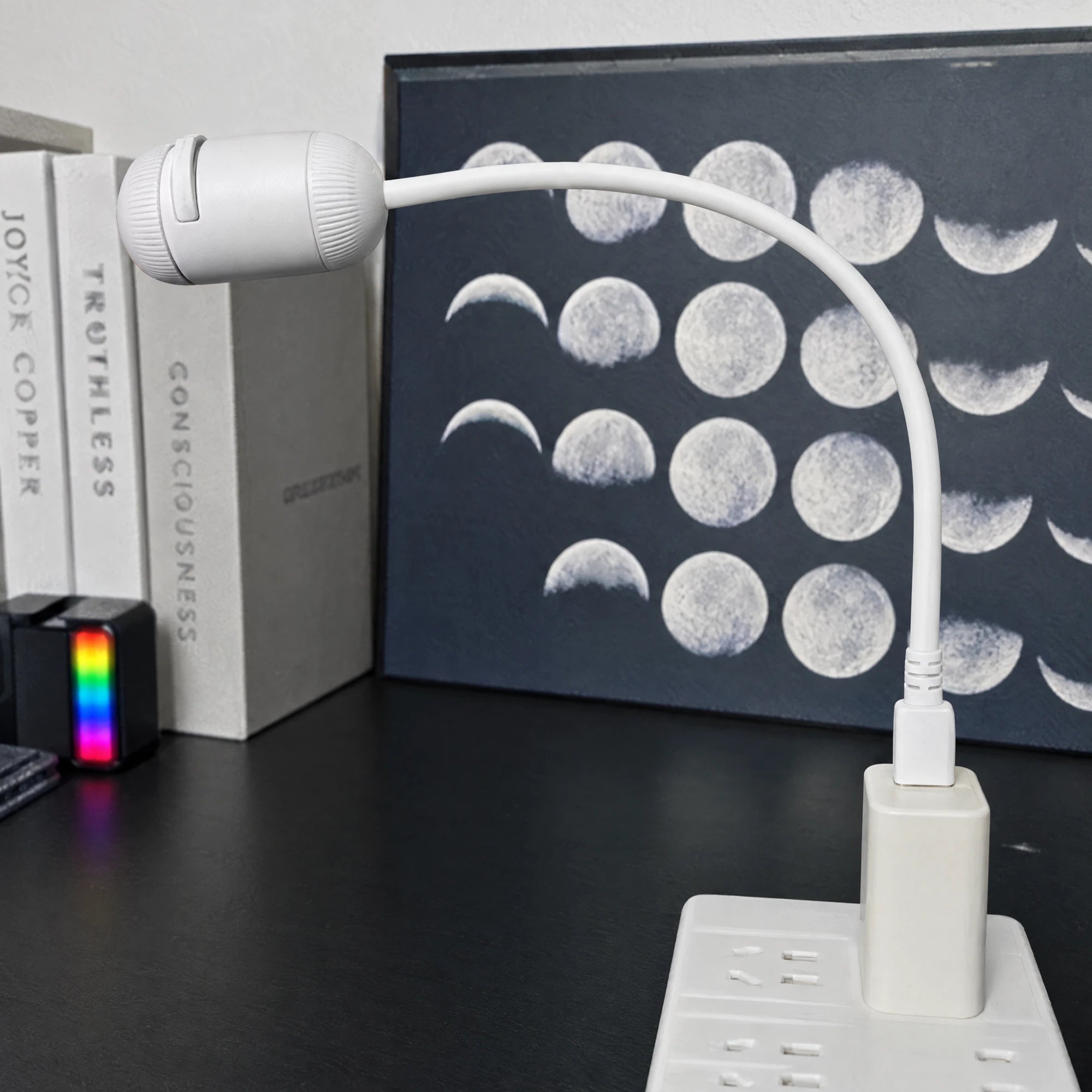 Projector on its flexible arm plugged into a USB wall socket on a desk